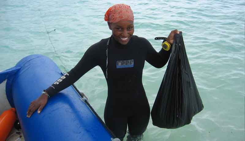 Instructor Grace holding a mesh bag of rubbish collected from the ocean on the dive